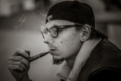 Close-up of young man smoking pipe outdoors