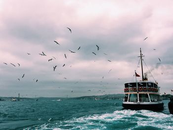 Ferry boat sailing in sea against cloudy sky