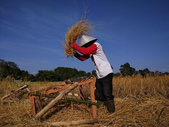 Rear view of man working at farm against clear sky