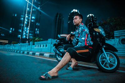 Side view of young man looking away in city at night