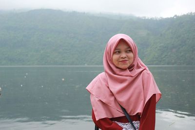 Portrait of woman standing against pink water