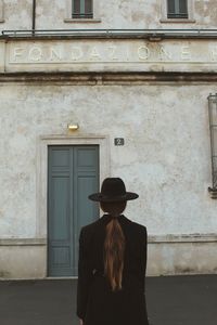 Rear view of woman standing against door of building