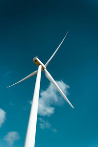 Low angle view of wind turbine against blue sky