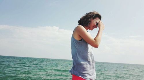 Young woman standing in sea against sky