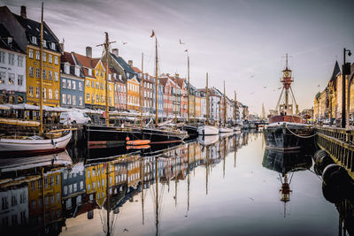 Boats moored at harbor against sky in city