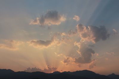 Silhouetted mountains against cloudy sky at dawn