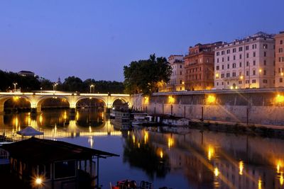 Illuminated bridge over river at dusk