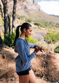 Side view of young woman standing on rock