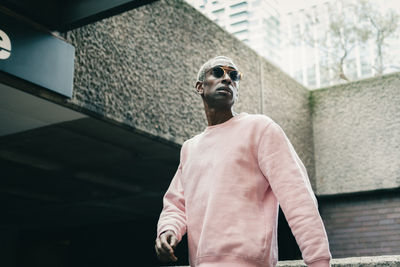 Low angle view of man looking away while standing against wall