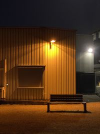 Empty bench against illuminated street light at night