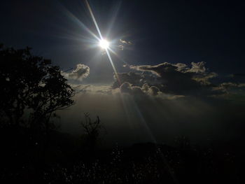 Low angle view of sun shining through clouds