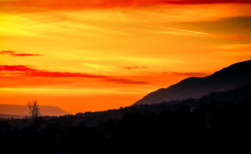 Scenic view of silhouette mountains against orange sky