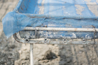 Close-up of old metal fence against blue wall