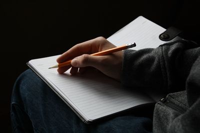 Midsection of man writing in book