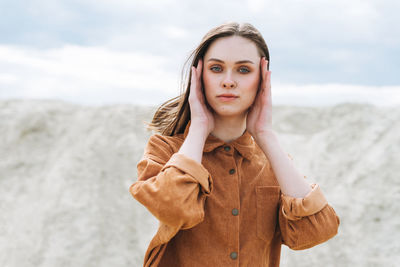 Fashion beauty portrait of young woman in brown organic velvet shirt on desert background