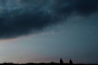 Silhouette people on land against sky during sunset