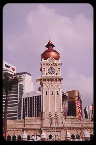 building exterior, architecture, built structure, transfer print, sky, auto post production filter, cloud - sky, city, cloud, cloudy, text, tower, clock tower, flag, travel destinations, day, incidental people, low angle view, street, outdoors