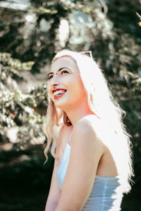 Smiling woman against plants during sunny day