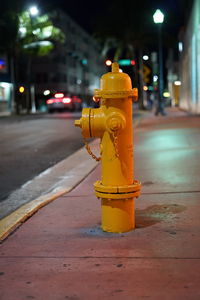 Close-up of fire hydrant on sidewalk at night