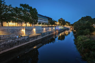 River by illuminated buildings against sky at night