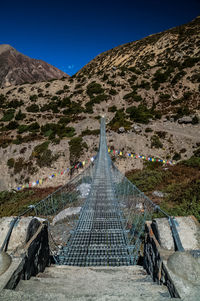 Footbridge over mountain against blue sky
