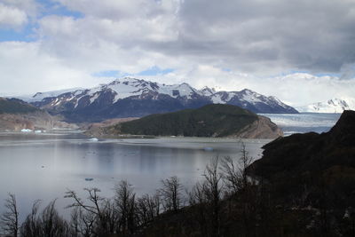 Scenic view of river and mountains against cloudy sky