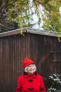 Portrait of senior woman standing against wooden house