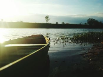 Boat moored on lake against sky during sunset