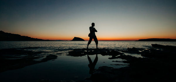 Silhouette man standing on beach against sky during sunset