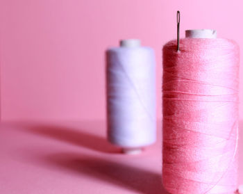 Close-up of spool of threads against pink background