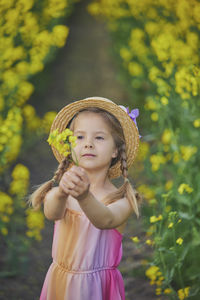 Portrait of young woman standing amidst flowering plants