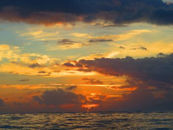 Scenic view of sea against dramatic sky during sunset