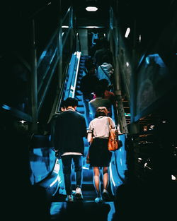 Rear view of people walking in illuminated building