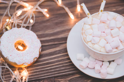 Close-up of marshmallows in cup with christmas lights on table