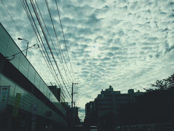 Low angle view of skyscrapers against cloudy sky