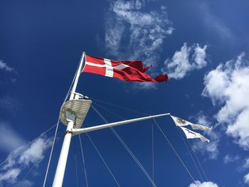 Low angle view of danish flag waving on sailboat against sea