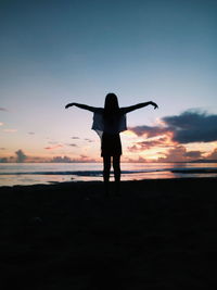 Rear view of silhouette man standing on beach during sunset