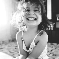 Portrait of cheerful girl sitting on bed at home