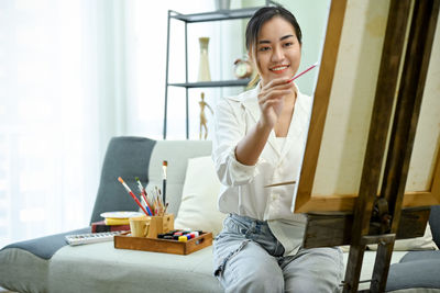 Young woman using mobile phone while sitting at home