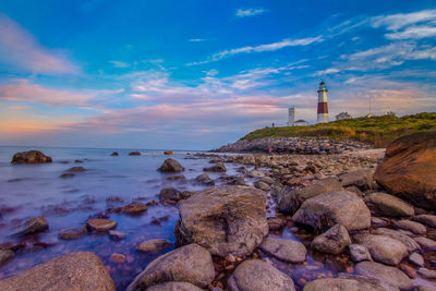 Rocks on beach by sea against sky