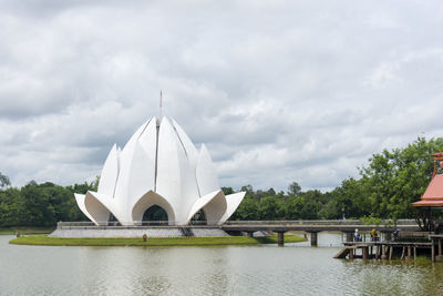 Bridge over lake by buildings against sky