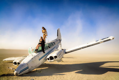 Airplane flying over sand against blue sky