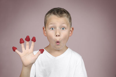 Portrait of boy holding apple against gray background