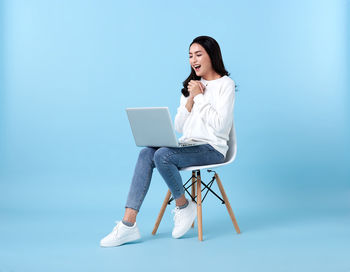 Young woman using mobile phone while sitting on chair