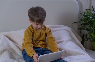 Side view of boy using digital tablet at home