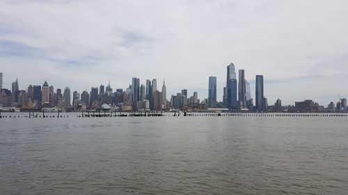 Sea and buildings in city against sky