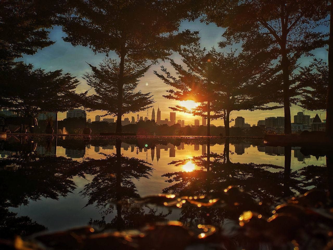 REFLECTION OF SILHOUETTE TREES IN LAKE AGAINST SKY DURING SUNSET