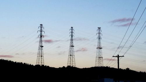 Low angle view of silhouette electricity pylon against sky