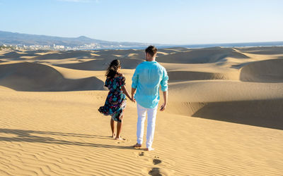 Rear view of woman walking at desert