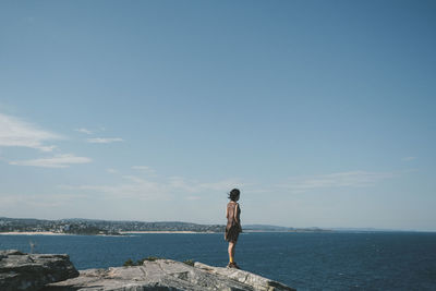 Rear view of man standing at beach against sky